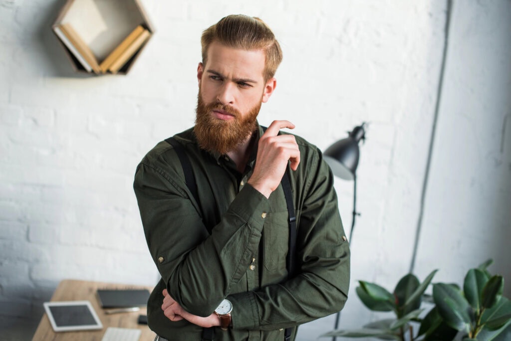 Thoughtful bearded businessman looking away in office