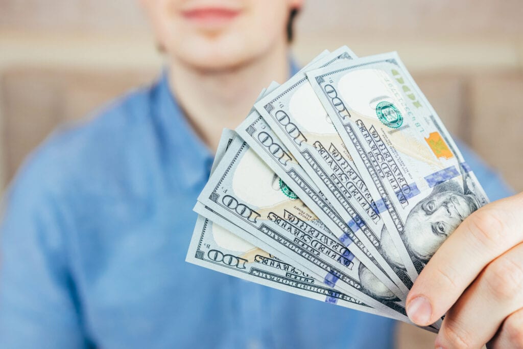Man holds fan of new dollar bills