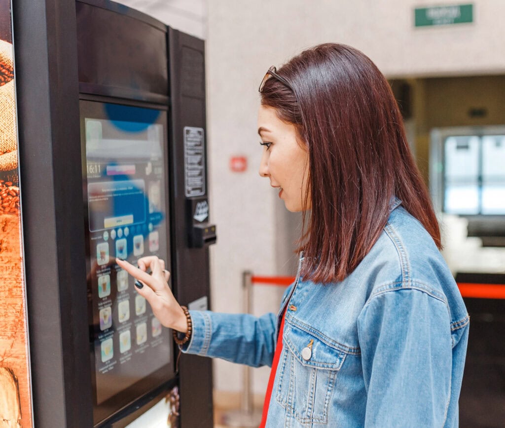Woman buying coffee from automatic vending machine