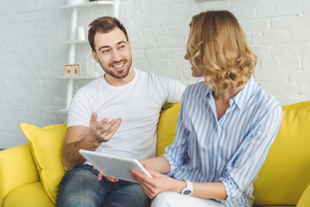 Smiling man talking to girlfriend with tablet in hands