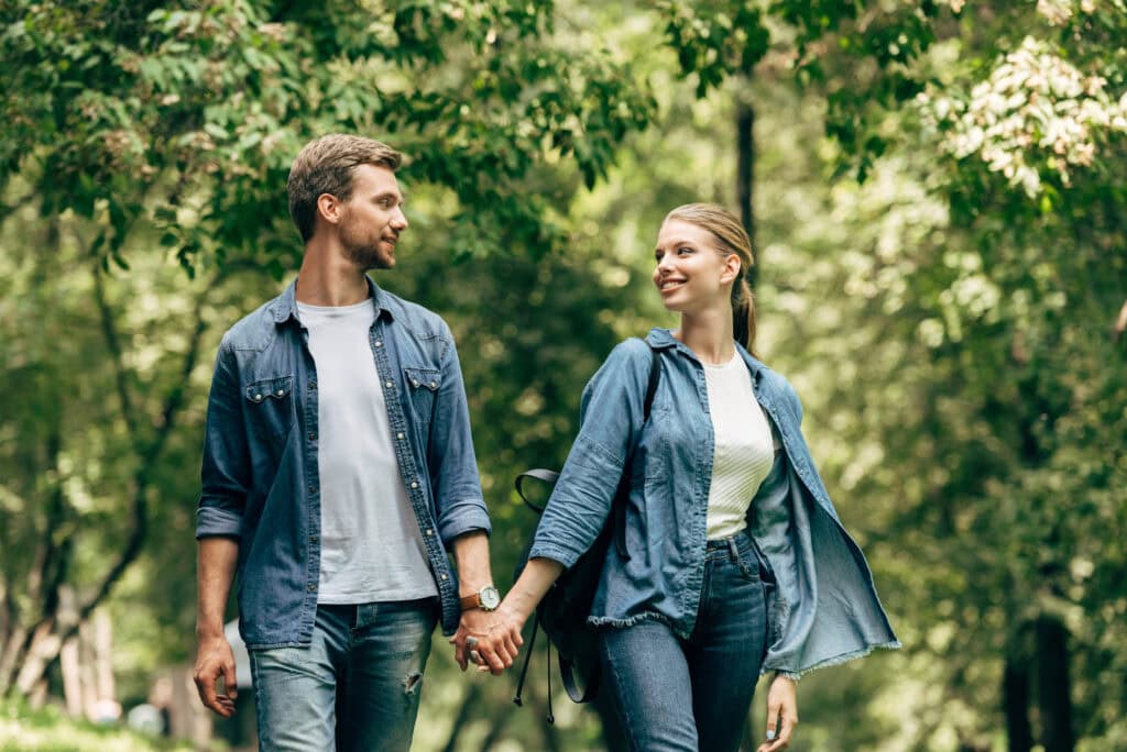 Beautiful young couple in denim shirts walking by park