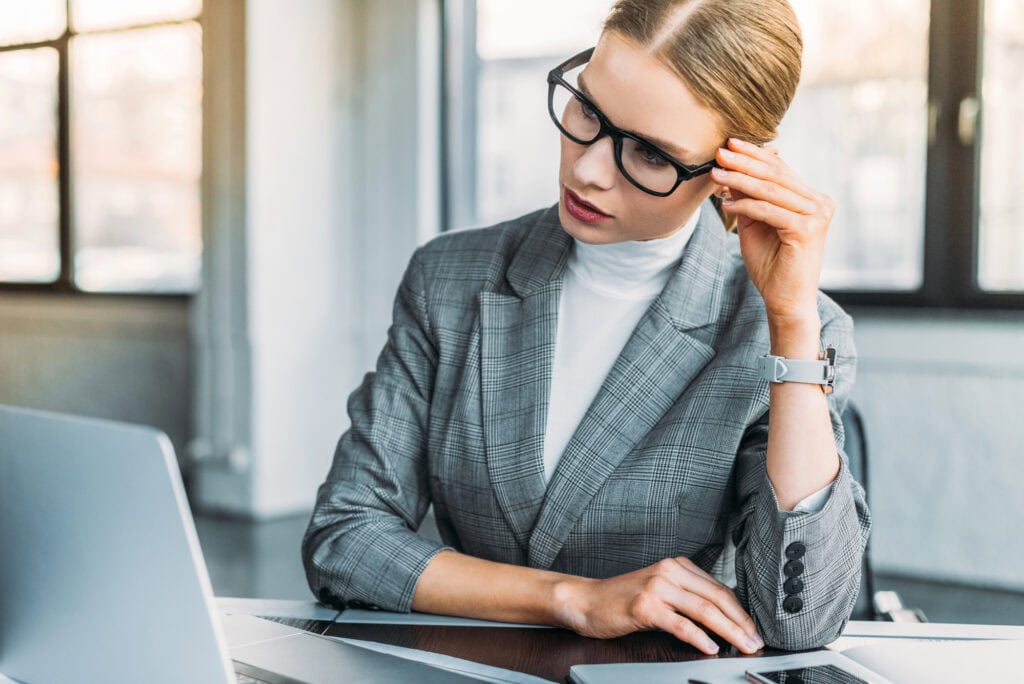 Businesswoman in glasses looking at laptop in office
