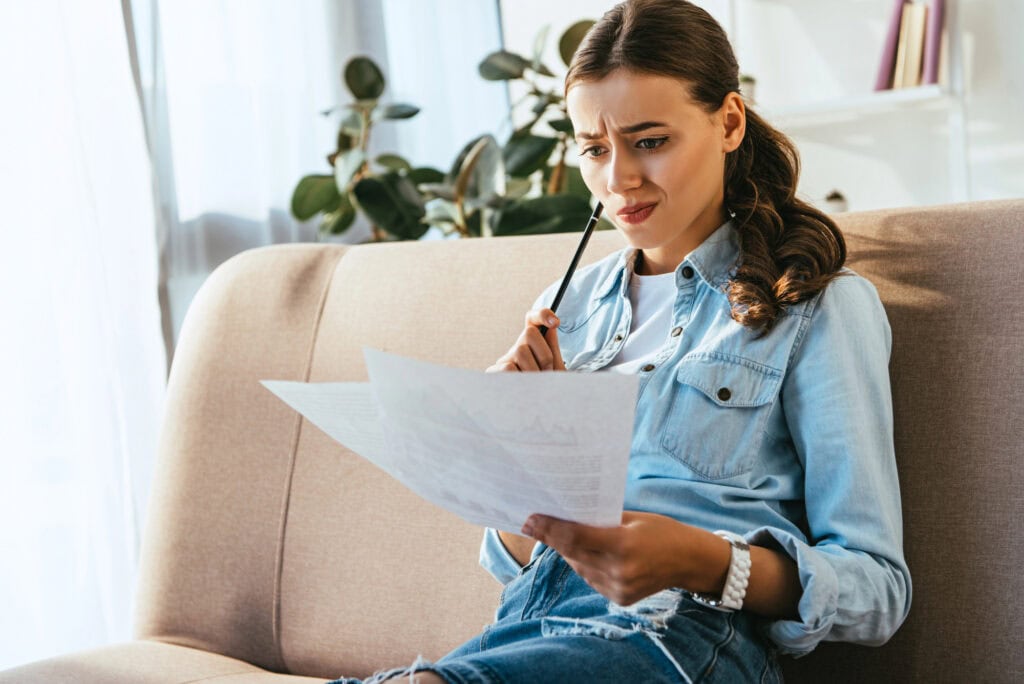 Portrait of young emotional businesswoman doing paperwork while remote working at home