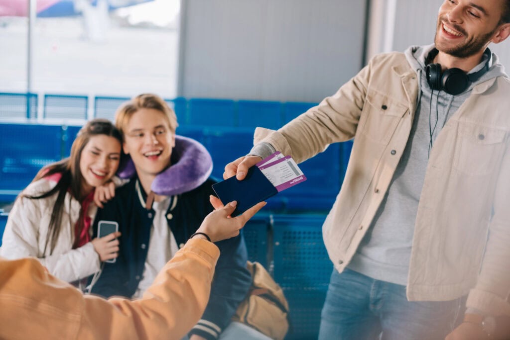 friends holding passport with boarding passes while waiting in airport
