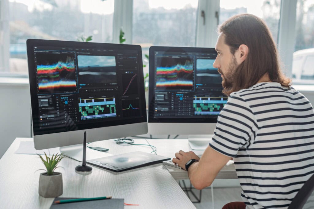 Editor sitting and working near computer monitors