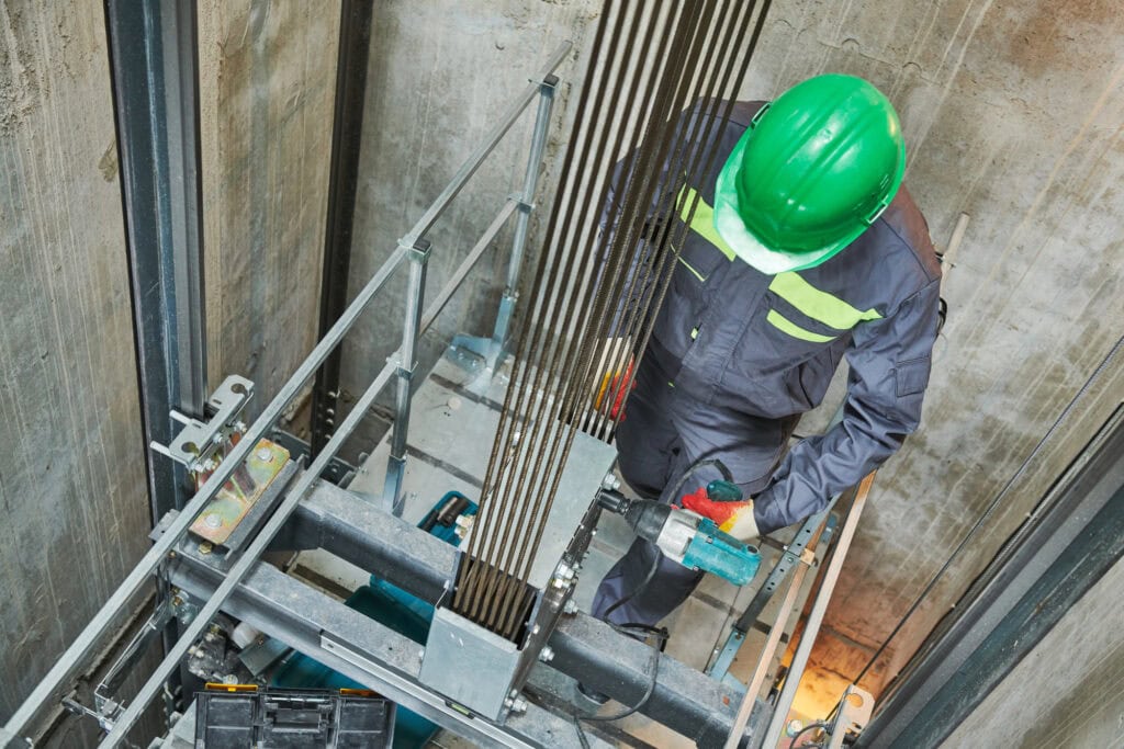 Lift machinist repairing elevator in lift shaft