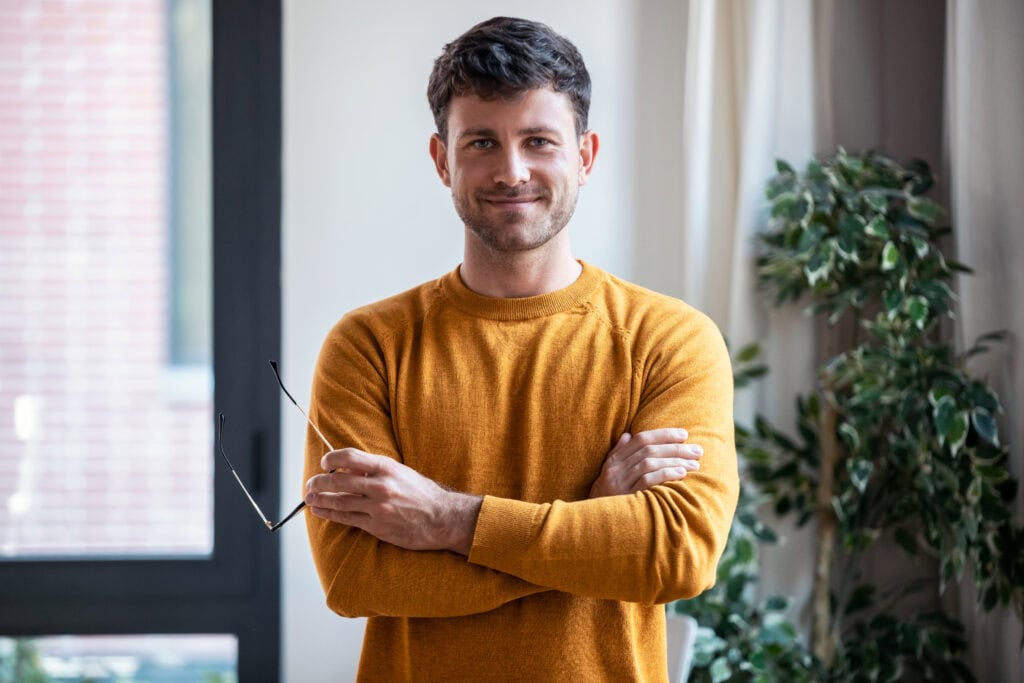 Smart handsome business man standing while crossing arms looking