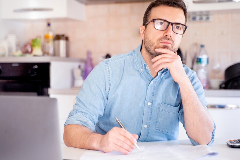 Man thinking and planning calculating home expenses