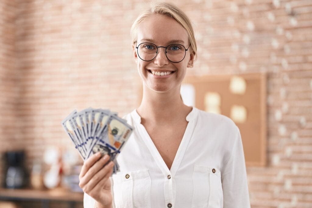 Woman business worker holding dollars at office holding dollars