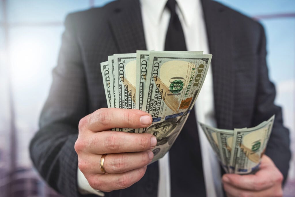 business man in classic black suit hold and check dollar