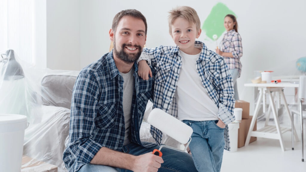 Father with paint roller posing with son