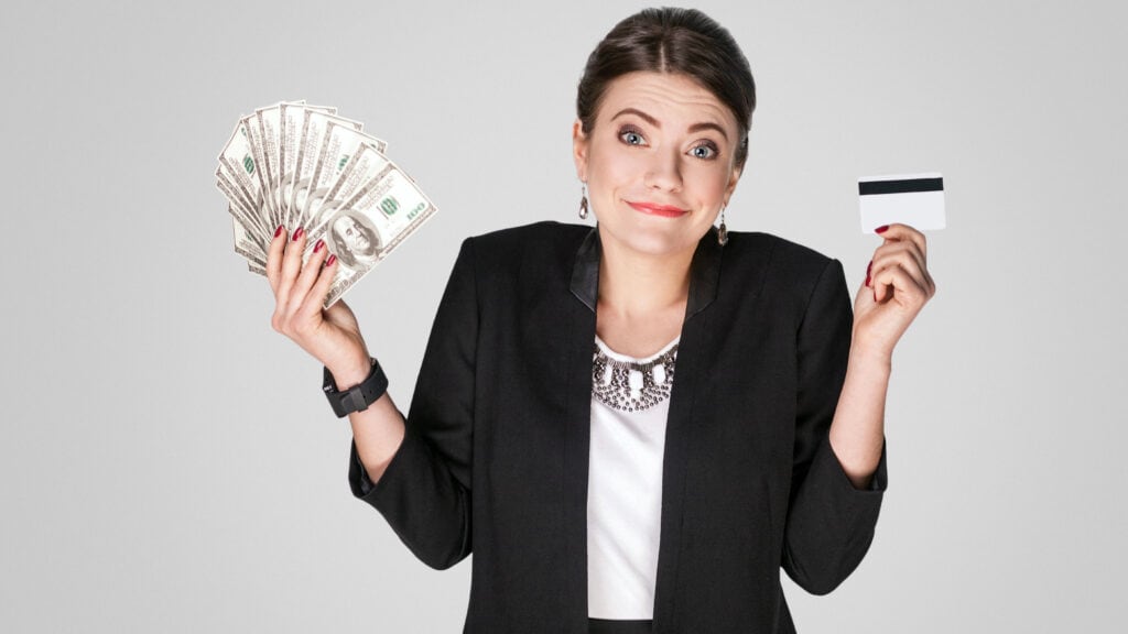 Businesswoman showing dollars banknotes and credit card on grey background