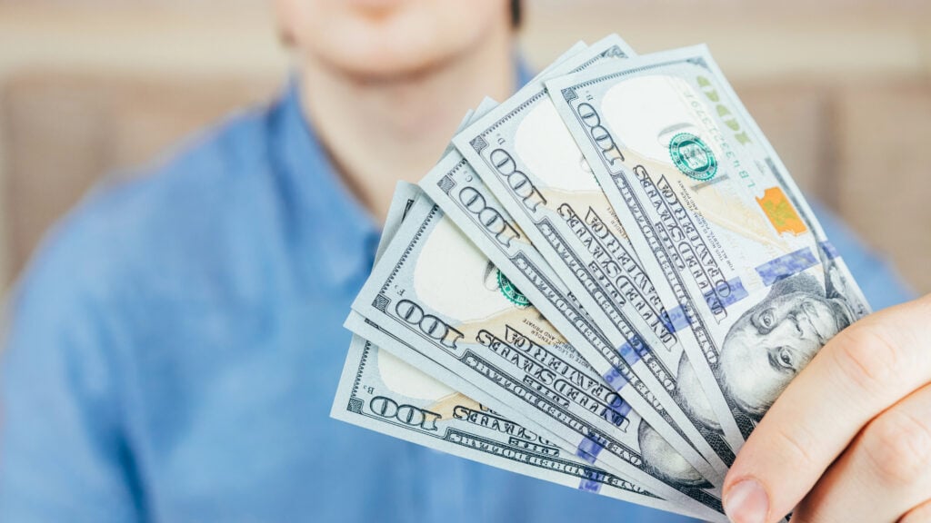 Man holds fan of new dollar bills