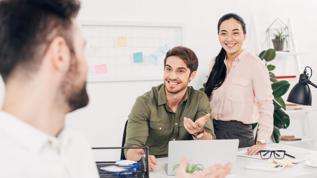 Young colleagues talking with coworker in modern office
