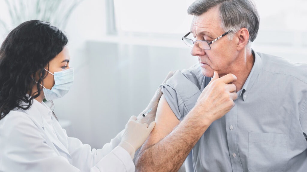 Doctor doing vaccination to elderly man