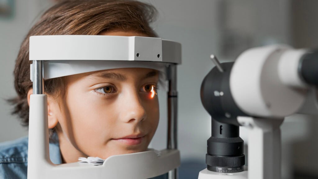 boy checking vision with tonometer at eye clinic