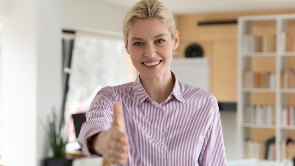 Pleasant young female hr manager reaching out hand.