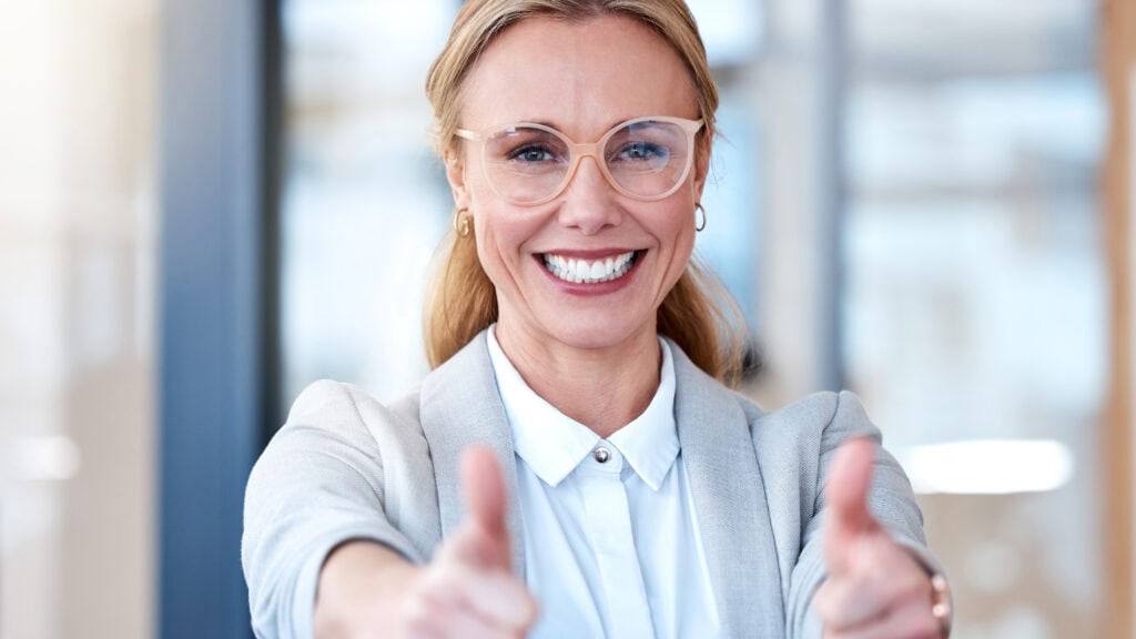 Businesswoman showing thumbs up in a modern office