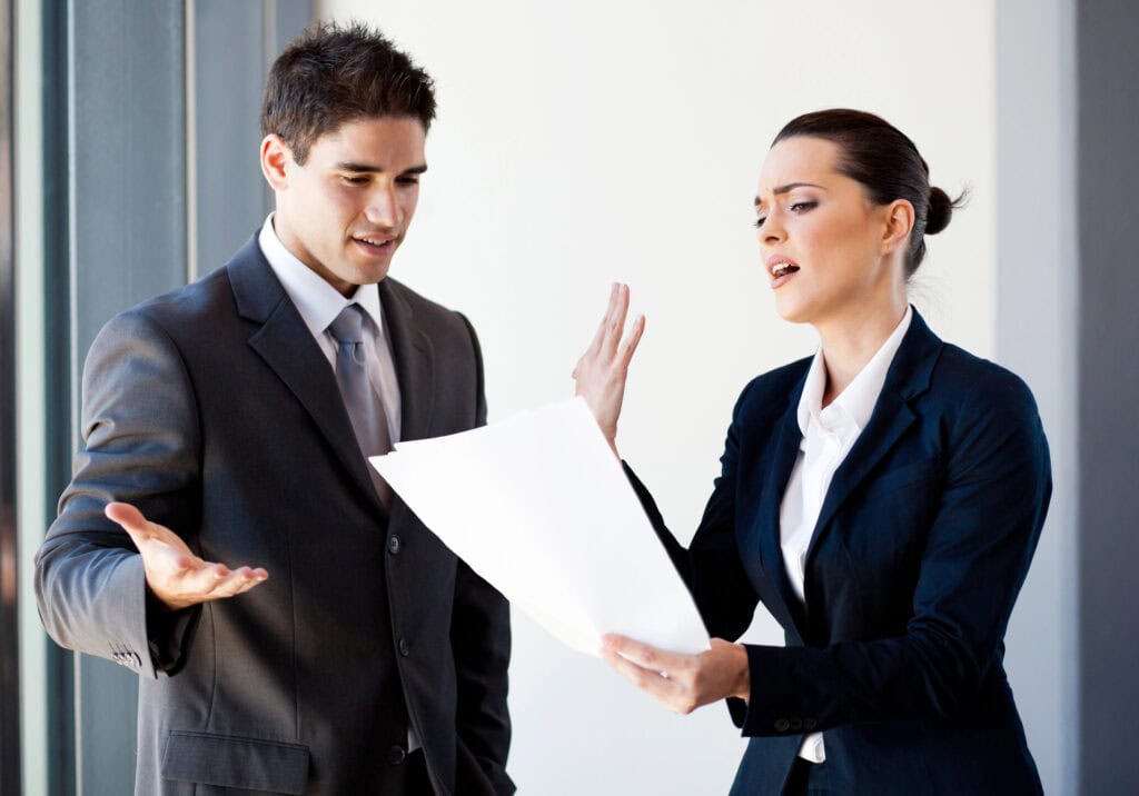 Two young colleagues arguing over paperwork in office