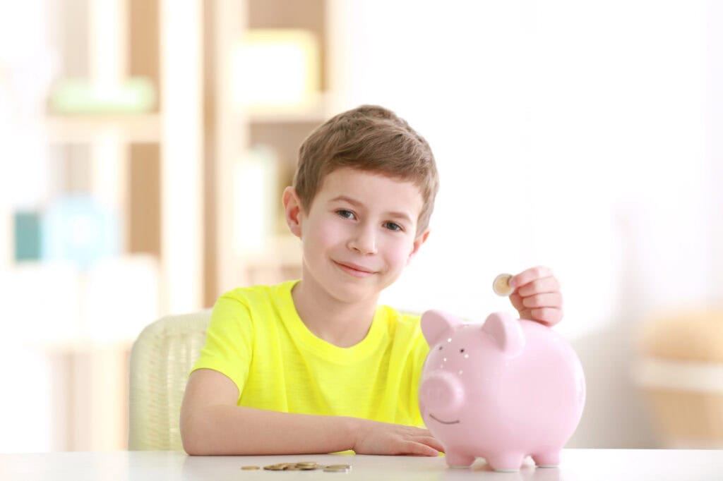 Boy saving coins in piggy bank