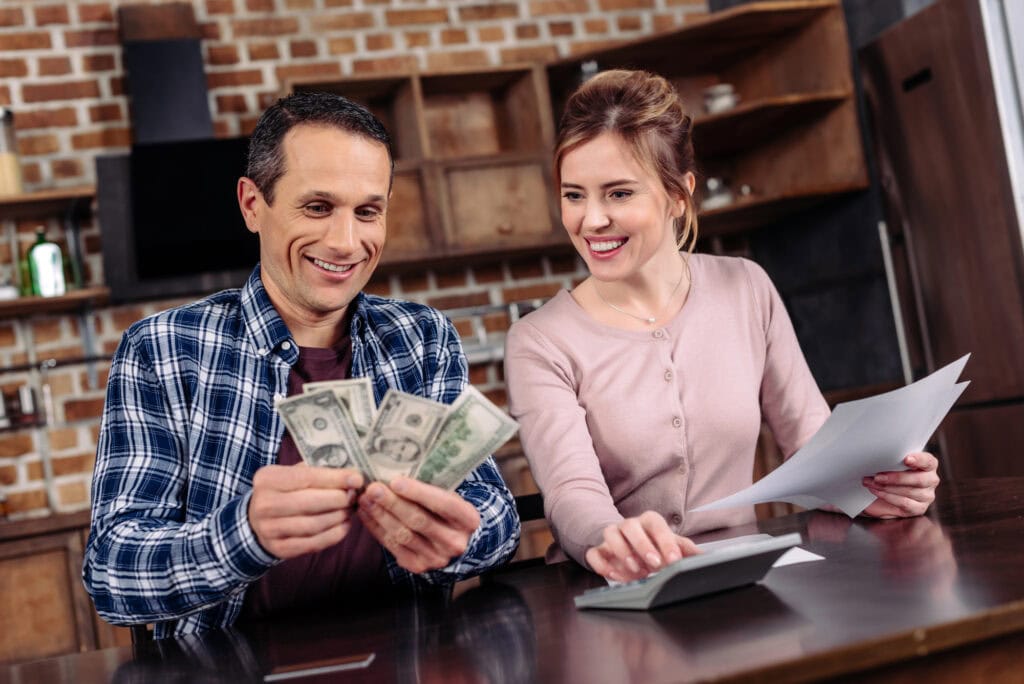 Portrait of happy couple counting money together at home