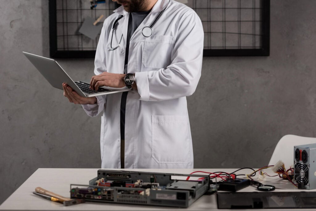 Cropped image of man in white coat and stethoscope over his neck using laptop