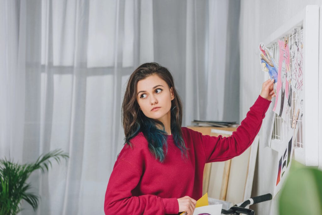 Attractive young girl pinning sketches on mood board