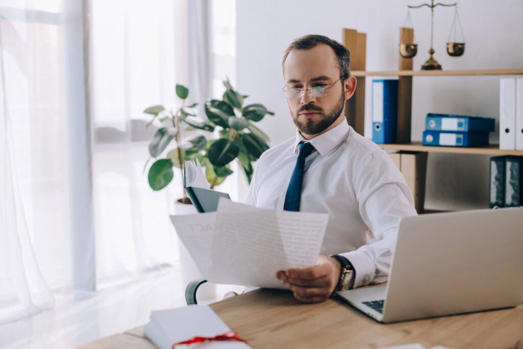 Portrait of focused lawyer with papers at workplace in office