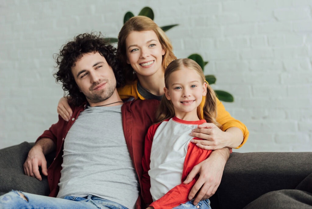 Happy parents with adorable little daughter spending time together at home