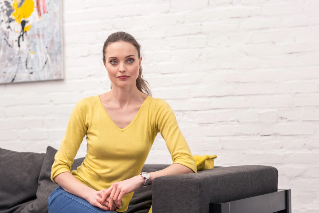 Attractive adult woman relaxing on couch at home and looking at camera