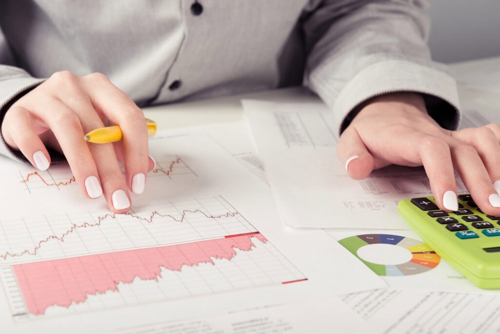 Female director working in office , analyzing business statistics, calculator, diagrams and charts on desk