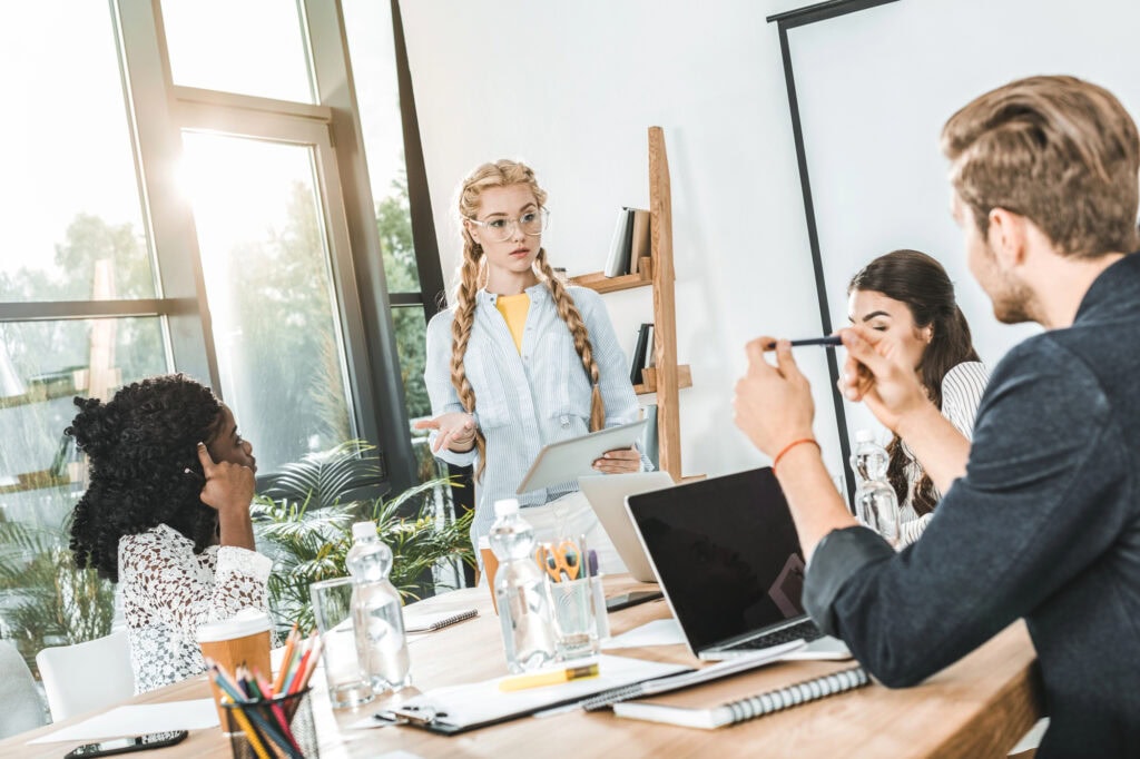 Multicultural group of business people discussing work while sitting at workplace in office