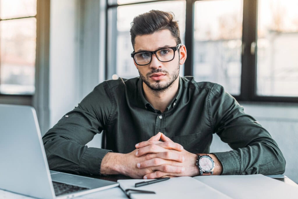 Businessman sitting at table in office and looking at camera