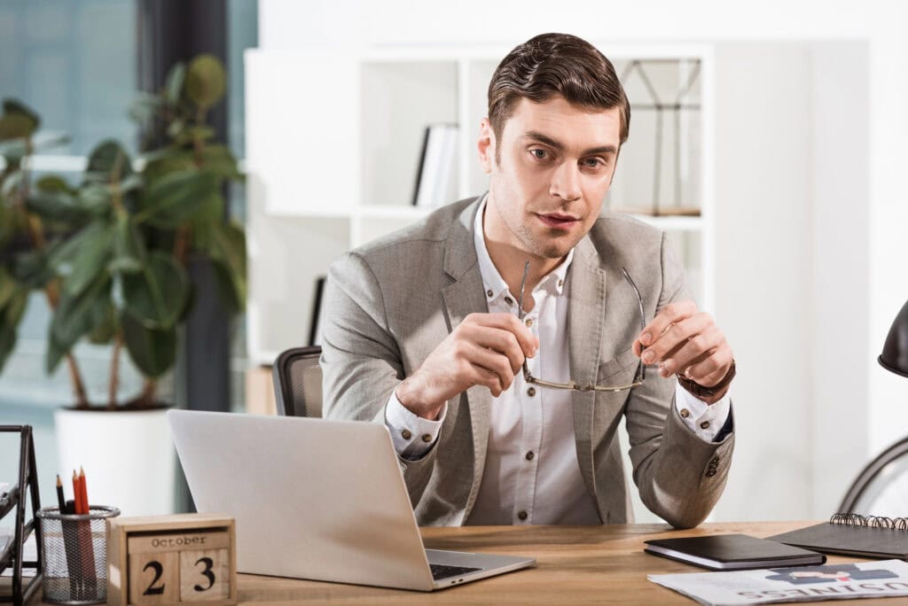 Handsome businessman with eyeglasses looking at camera at office