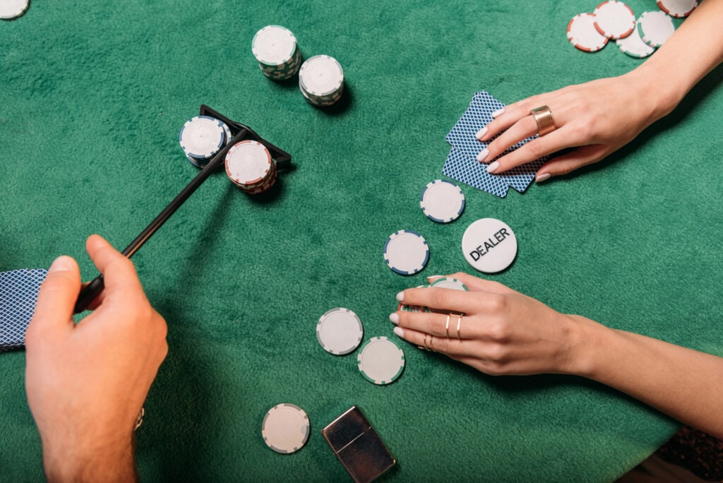 Cropped image of woman and croupier playing poker at table in casino