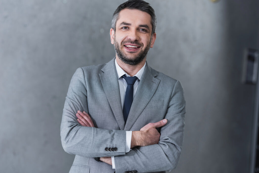 Confident handsome businessman standing with crossed arms and smiling at camera