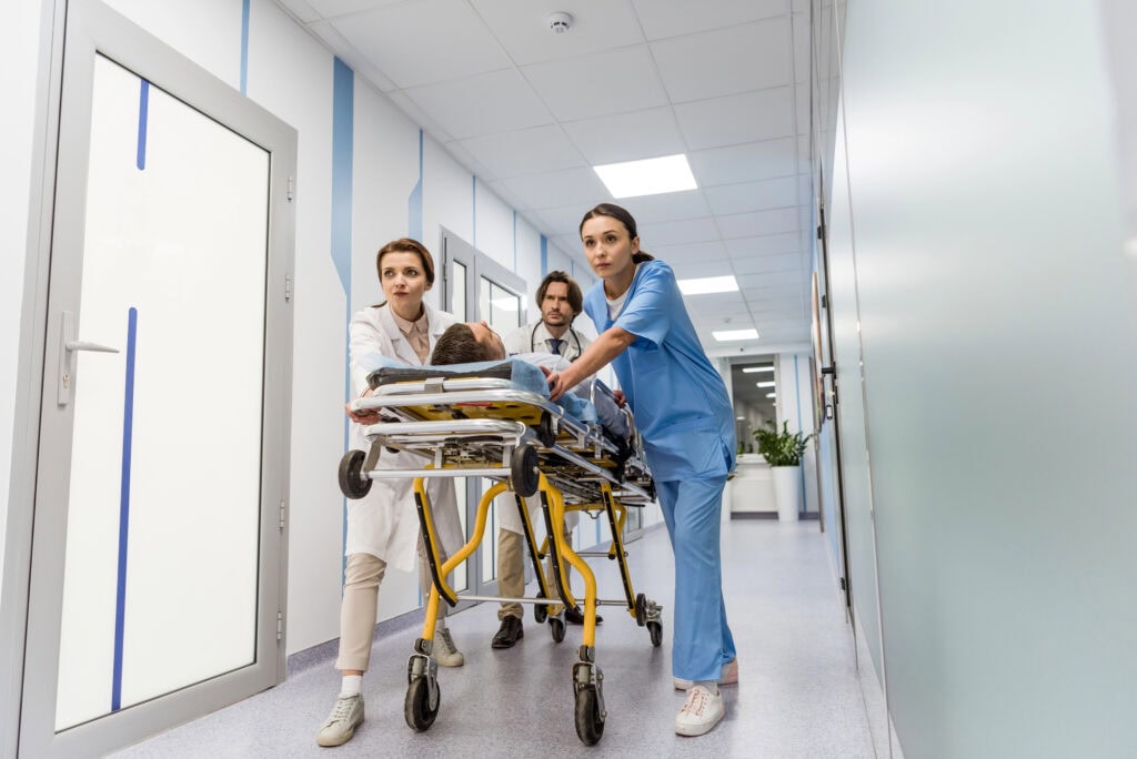 Worried doctors and nurse transporting unconscious patient on gurney