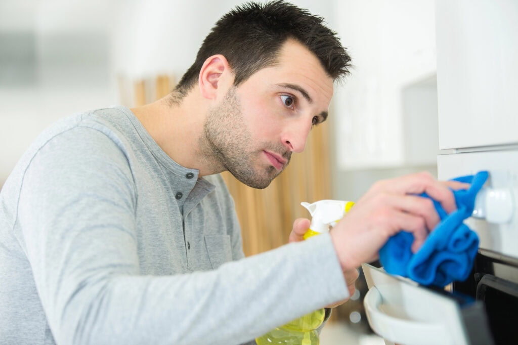 Man cleaning oven in kitchen