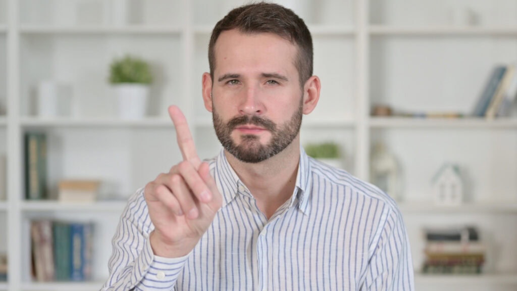 Portrait of Young Man saying No with Finger Sign
