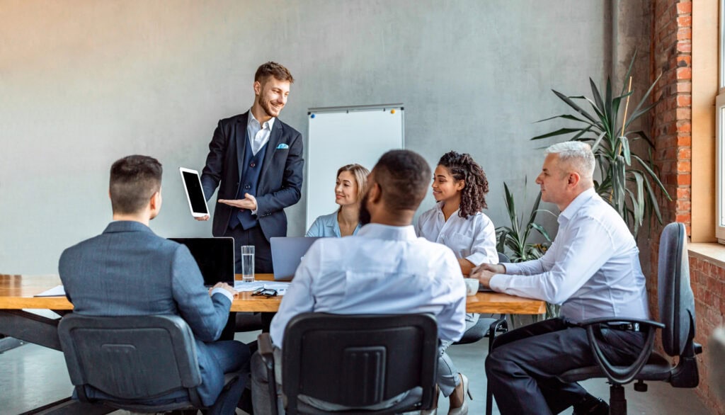 Businessman Presenting Project To Coworkers During Corporate Meeting Indoors