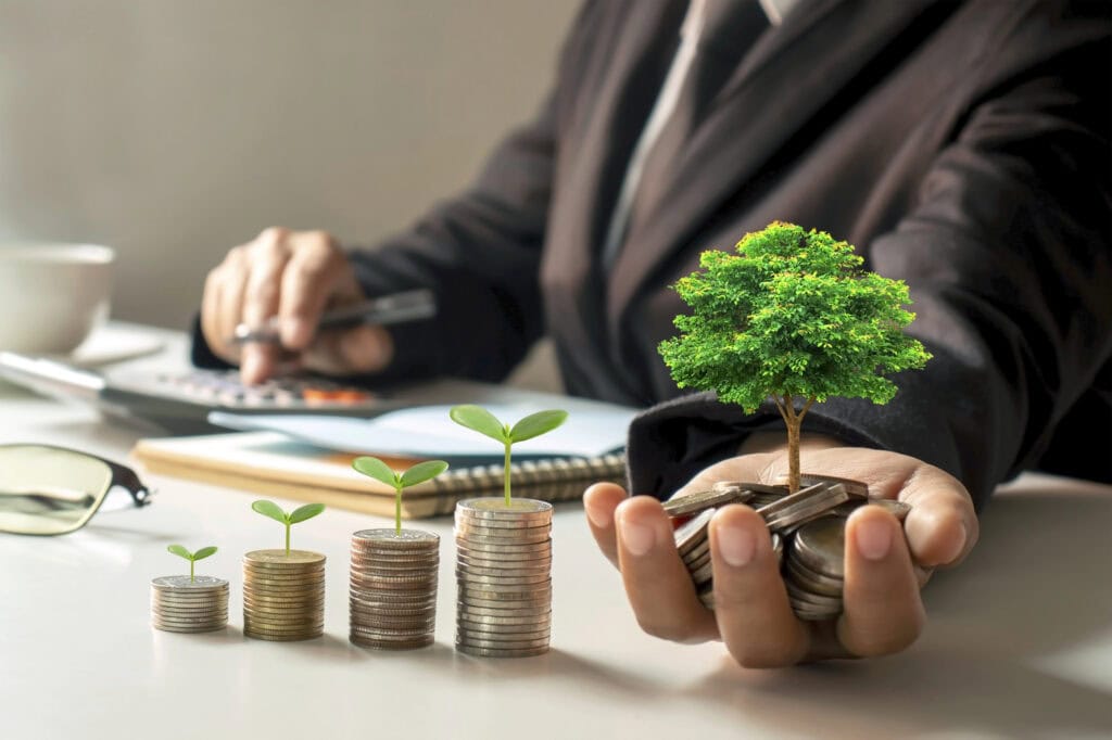 A growing tree on a pile of money in the hands of a businessman and a tree growing on a stack of coins financial ideas and financial growth.