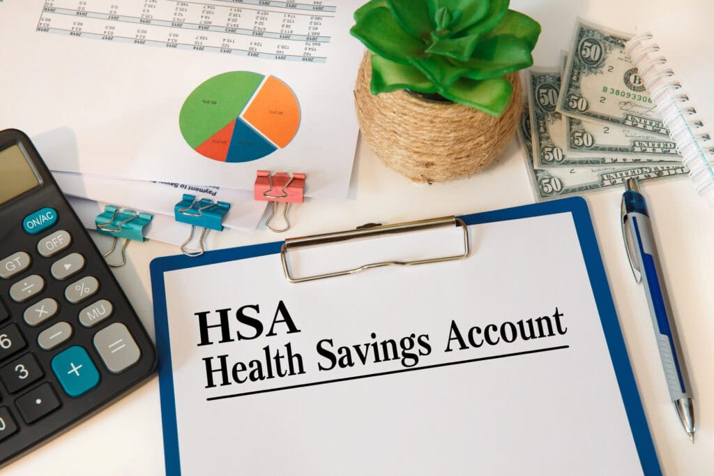Paper with Health Savings Account HSA on a table, calculator and documents