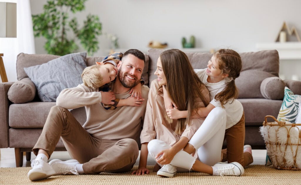 Happy family mother father and children at home on floor next to the sofa