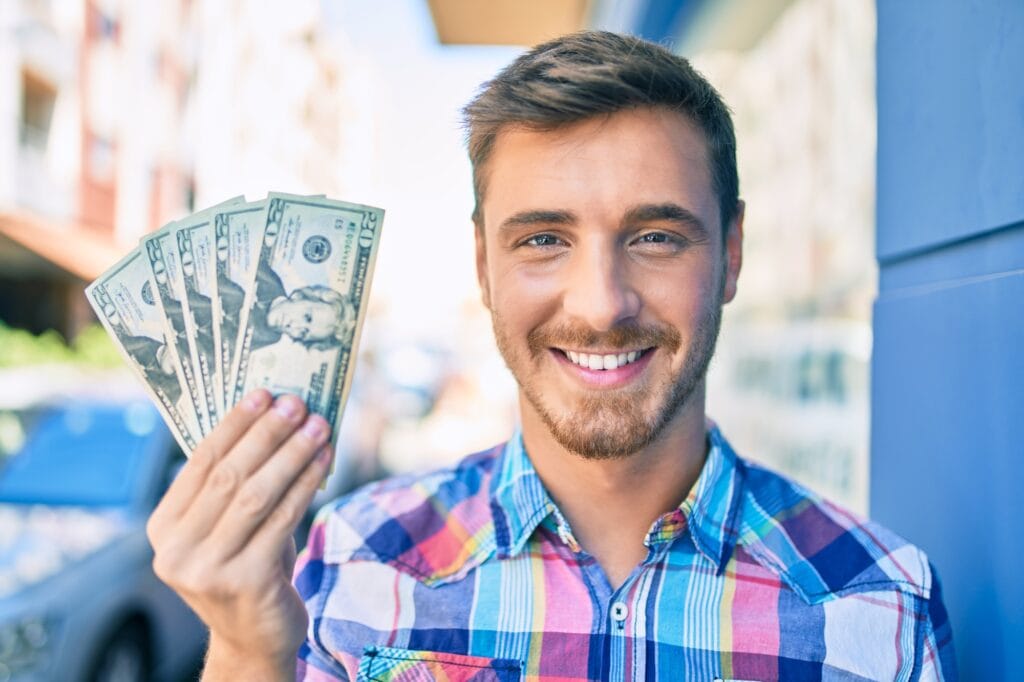 Man smiling happy holding dollars.