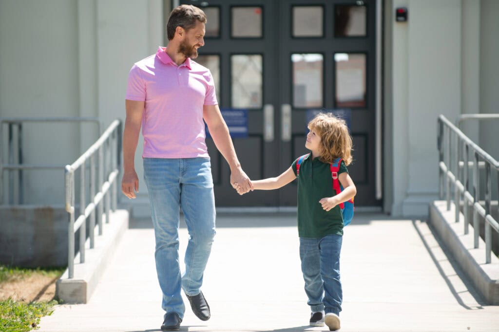Father supports and motivates son. Parent taking child to school.