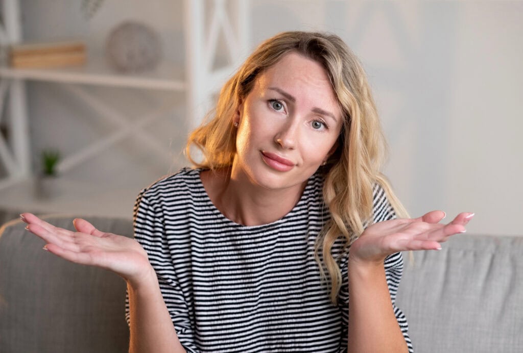 Confused woman sitting on couch at home