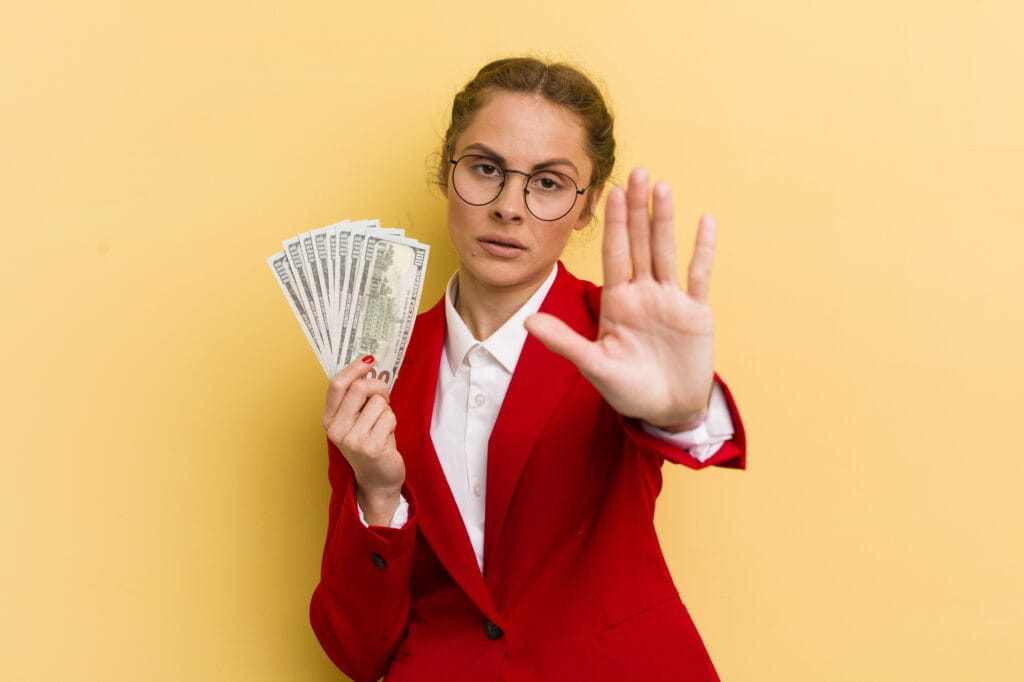 Young pretty woman looking serious showing open palm making stop gesture. money concept