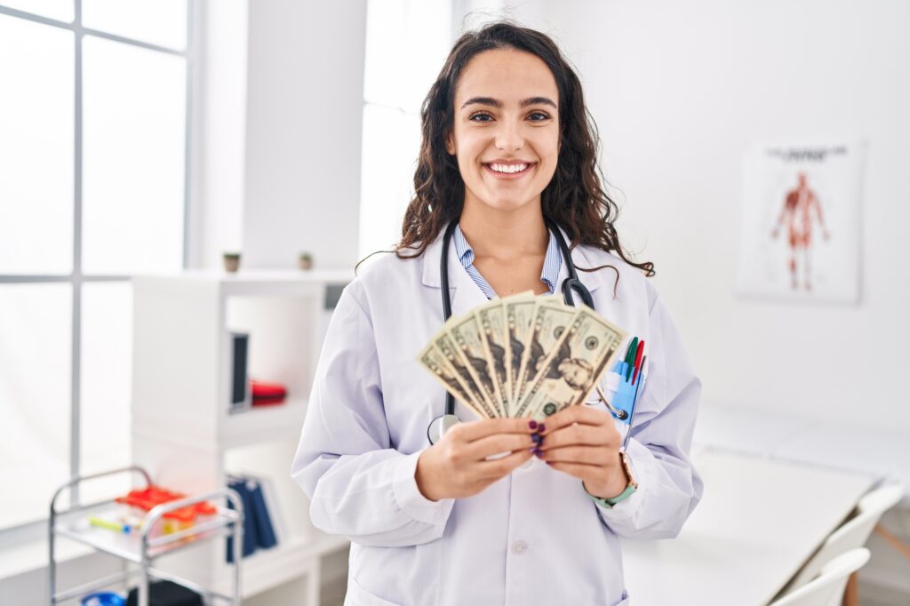 Young doctor woman holding money smiling.