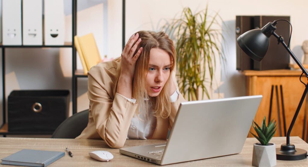 Irritated shocked young business woman while working on laptop