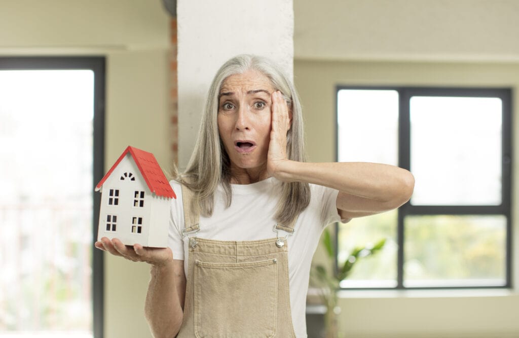 woman feeling extremely shocked and surprised. with a house model